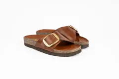 Sandalias bajas marrones de cuero, con plantilla de corcho y suela de goma. Tira ancha sobre el empeine con hebilla dorada ajustable.