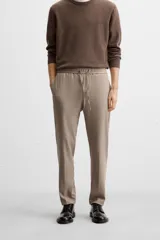 Pantalón color arena de corte recto, confeccionado en tejido elástico. Cuenta con cintura elástica ajustable con cordón, bolsillos laterales y bolsillos de vivo en la parte trasera.