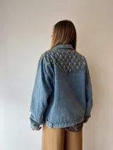 Campera de jean celeste con tachas doradas en forma de estrella en la parte superior de la espalda y los puños.