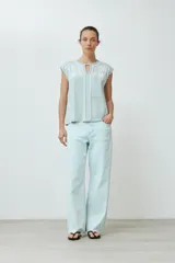 Remera de manga corta color verde agua con bordado floral blanco en la zona del pecho y cuello con abertura en forma de lágrima.