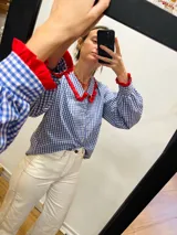 Camisa de algodón a cuadros azules y blancos con cuello y puños con volados rojos.