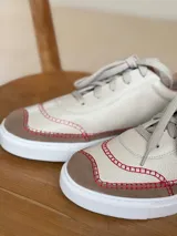 Championes de cuero color beige con puntera de gamuza marrón y costuras rojas.