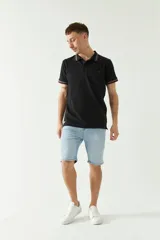 Chomba azul marino de manga corta con cuello polo y detalles de líneas grises en cuello y mangas. Tiene logo bordado en el pecho. Corte regular.