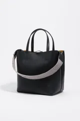 Bolso de hombro estructurado de piel vacuna negra, con doble asa de mano y asa regulable de tejido a rayas. Presenta cierre de cordón, logo metálico frontal y bolsillo interior con cierre de cremallera.