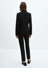 Blazer negro entallado con solapas de muesca, hombros estructurados, abertura posterior y dos bolsillos de ribete delanteros.