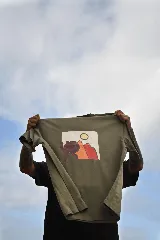 Remera color verde oliva con efecto gastado, de manga corta y cuello redondo. Presenta un pequeño estampado en el pecho de una figura humana estilizada en color marrón.