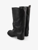 Bota de caña alta confeccionada en cuero negro con sutiles matices marrones de efecto desgastado. Presenta un diseño de caña doble o solapada que cubre parte del empeine, silueta recta, punta redondeada y taco bajo cuadrado.