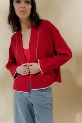 Chaqueta roja de tejido de punto con calce relajado y hombros caídos. Lleva solapa ancha acanalada terminada con cadenetas en contraste. Largo a la cadera y manga larga.