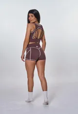 Conjunto deportivo color marrón, compuesto por un top con breteles anchos y logo 'bk.' estampado, y un short de calce ajustado.