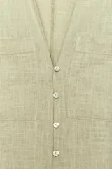 Vestido camisero largo color verde claro, confeccionado en lino. Tiene cuello solapa, escote en V, manga tres cuartos con trabilla y botón, bolsillos delanteros de plastrón, aberturas laterales en el ruedo y cierre frontal con botones.