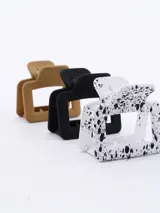 Set de tres pinzas para el pelo tipo clip, de plástico transparente en color negro, marrón y beige.