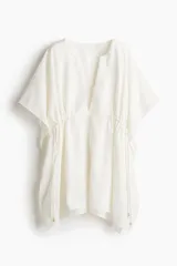 Túnica playera blanca de manga corta con escote en V y cordones ajustables en la cintura.