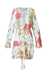 Salida de playa estilo kimono con estampado floral en tonos rosa, verde y amarillo sobre fondo blanco. Presenta cordón ajustable en la cintura con borlas decorativas y detalles de puntilla en mangas y ruedo.