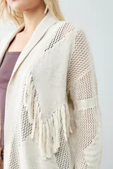Ruana color beige claro con flecos en el borde inferior.