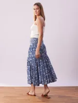 Falda midi de algodón estampada con flores blancas sobre fondo azul. Tiene pretina ancha elastizada en punto smock, ruedo con volados y forro interno a tono.