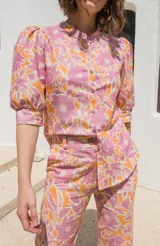 Camisa estampada con flores color rosa y naranja, de lino, con cuello mao, mangas cortas abullonadas y cierre frontal con botones.