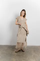 Vestido largo tejido color beige, con escote en V y flecos en el ruedo.