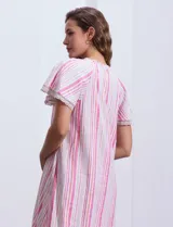 Vestido corto de lino a rayas verticales color lila y blanco, con cuello fruncido, escote en V y lazo de ajuste. Mangas cortas con puntilla de crochet.