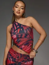 Conjunto de top asimétrico y falda pareo con estampado abstracto en tonos rojo y negro.
