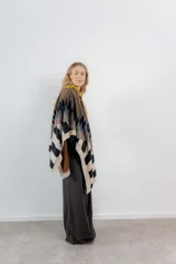 Ruana de tejido de punto con diseño geométrico en tonos beige, marrón, rojo y negro.