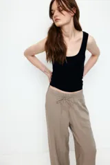 Pantalón de viscosa color beige, de corte amplio, tiro alto, cintura elastizada con cordón de ajuste, bolsillos laterales y piernas rectas.