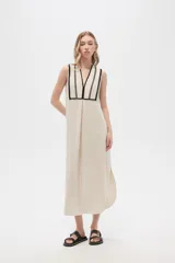 Vestido largo color crema con rayas verticales finas en negro, escote en V con ribete negro y corte holgado.