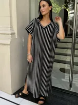 Vestido largo de tejido a rayas horizontales en tonos beige y blanco, con escote en V y mangas cortas tipo murciélago. Presenta tajos laterales en el ruedo.