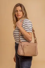 Bandolera de diseño moderno, color beige rosado, con correa regulable y bolsillo frontal con cierre.
