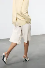 Zapato de tacón en piel color beige con abertura lateral, punta fina y cierre con tira ajustable. Tacón alto fino de 10,5 cm.