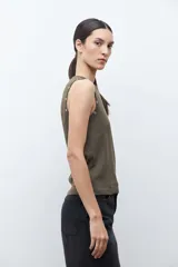 Top sin mangas color verde oliva, con cuello redondo y ojalillos metálicos decorativos a lo largo de la sisa.