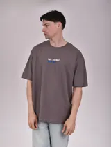 Remera blanca de corte recto con estampado de un auto clásico frente a un skyline urbano.