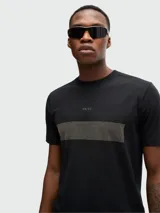 Camiseta negra de algodón elástico con cuello redondo y manga corta. Presenta una banda horizontal con diseño a cuadros y el logo de la marca en el pecho.