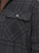 Sobrecamisa a cuadros gris y negra de manga larga con cierre de botones y bolsillos en el pecho.