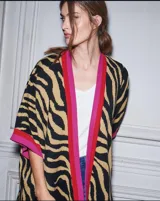 Ruana larga con estampado animal print de cebra en tonos beige y negro, con borde en color fucsia.