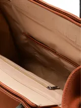 Cartera de cuero gamuza color marrón, con doble asa corta y correa larga desmontable. Tiene logo metálico de la marca en el frente, cierre central, bolsillo exterior con cierre y bolsillo interior con cierre.