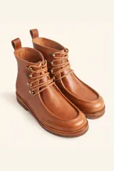 Bota de cuero vacuno color bordó con acabado brillante, diseño tipo botineta con cordones y ganchos metálicos. Presenta suela de goma tipo crepe con plataforma y costuras visibles en la puntera.