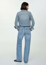 Chaqueta de jean celeste de corte clásico, con cuello camisero, cierre frontal con botones metálicos, bolsillos delanteros con solapa y puños abotonados.