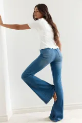 Top blanco de punto acanalado, corte ajustado y corto, con escote en V ribeteado en encaje y cierre frontal con tiras finas.