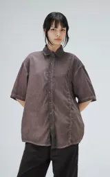 Camisa manga corta color gris con efecto desgastado, corte holgado y cierre frontal con botones.