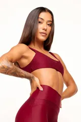 Top deportivo reversible color bordó, con diseño slim, tirantes finos y espalda descubierta. Un lado tiene acabado brillante y el otro textura 3D tipo colmena.