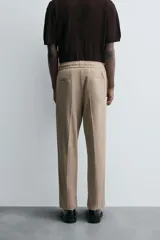 Pantalón color topo de corte recto, con cintura elástica ajustable con cordón, bolsillos laterales y bolsillos de vivo en la espalda.
