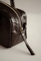 Cartera tipo baguette de cuero color amarillo pálido, con asas cortas y estructura rectangular.