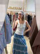 Falda larga de jean azul con bordados florales en lurex plateado, cintura elastizada y corte escalonado.