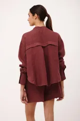 Camisa de lino color vino tinto, con cuello mao y botones blancos. Presenta un corte holgado y manga larga con puños abotonados.