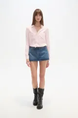 Camisa de viscosa color crema con finas rayas verticales negras, corte al cuerpo, cuello camisa y dos bolsillos frontales con tapa. Posee botones frontales y mangas largas con puño.