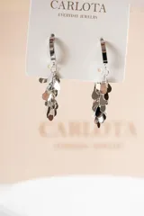 Aros colgantes plateados con cierre de aro y múltiples dijes metálicos en forma de gota.