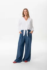 Camisa blanca de lino con mangas largas, diseñada para usarse anudada al frente o suelta.