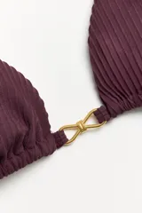 Corpiño de bikini tipo triángulo con textura acanalada color vino tinto. Presenta tirantes finos ajustables y un detalle metálico dorado con forma de infinito o lazo en el centro del busto.