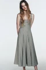 Vestido midi de tirantes con escote cuadrado y falda amplia con godets, confeccionado en tela con estampado de cuadros vichy en blanco y negro.