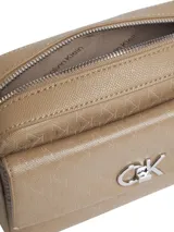 Cartera bandolera color beige con monograma CK grabado en toda la superficie. Tiene correa de cadena plateada, bolsillo externo con cierre giratorio y herrajes plateados.
